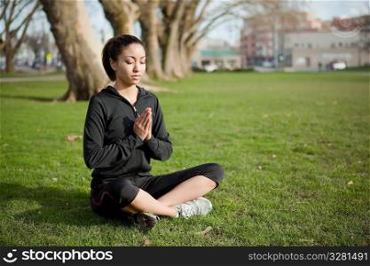 A beautiful black woman doing yoga meditation outdoor in a park