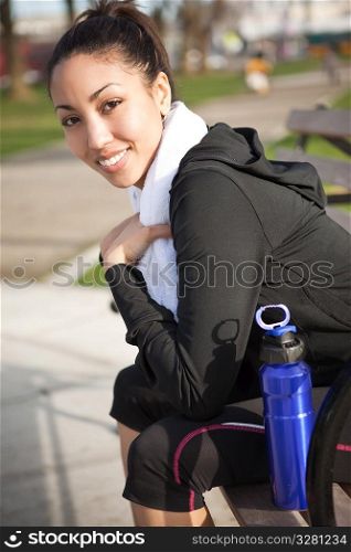 A beautiful black woman sitting on a park bench after exercise