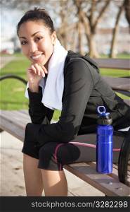 A beautiful black woman sitting on a park bench after exercise