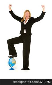 A beautiful blond businesswoman stands with her foot on a globe and raising her arms in conquering celebration