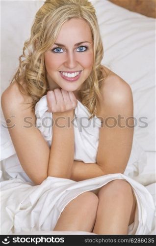 A beautiful blond haired blue eyed young woman naked and arapped in white sheets on her bed