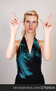 A beautiful blond woman holding her hands up and makinga sign, to the photographer, on light gray background.