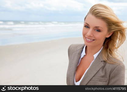 A beautiful blond young woman at the beach illuminated by natural light with her hair blowing in the wind