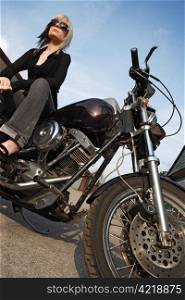 A beautiful blonde female sitting on a motorcycle.