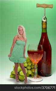 A beautiful blonde woman standing beside a giant wine bottle and glasse