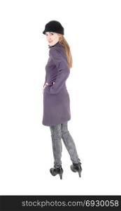 A beautiful brunette woman standing in a blue winter coat and hat,standing in profile, isolated for white background