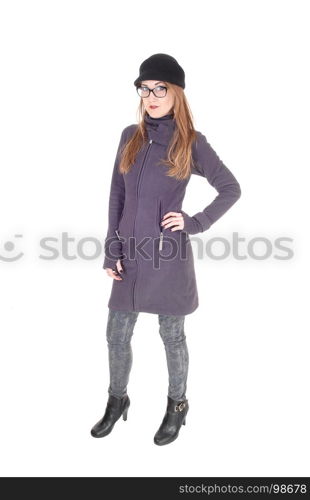 A beautiful brunette woman standing in a blue winter coat and hat,wearing glasses, isolated for white background