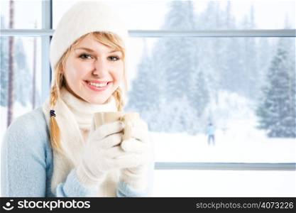 A beautiful caucasian girl drinking hot coffee at a ski resort during a snowy day