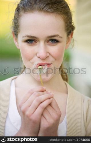 A beautiful caucasian teenage girl outdoor in summer blowing dandellion