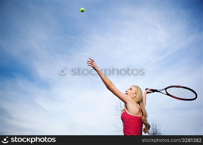A beautiful caucasian tennis player serving the ball on the tennis court