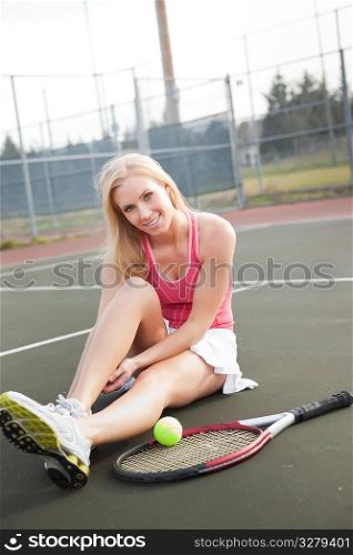 A beautiful caucasian tennis player stretching on the tennis court