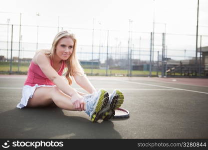 A beautiful caucasian tennis player stretching on the tennis court