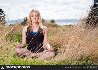 A beautiful caucasian woman doing yoga meditation outdoor in a park