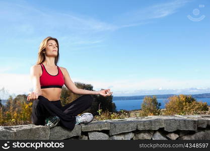 A beautiful caucasian woman doing yoga meditation outdoor in a park