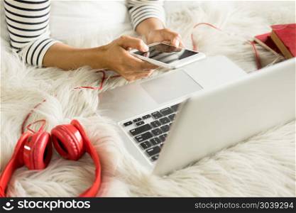 A beautiful caucasian woman lying down on the bed pretty girl using cellphone and using a laptop notebook on bed, resting.. A beautiful caucasian woman lying down on the bed pretty girl us