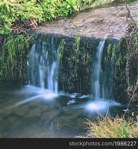 A beautiful clean brook in the countryside with a sink and running water.