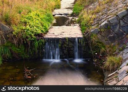 A beautiful clean brook in the countryside with a sink and running water.