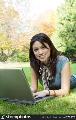 A beautiful college student working on her laptop outdoor