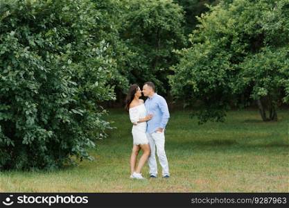 A beautiful couple in love hugs in a summer park on a walk
