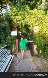 A beautiful cozy courtyard, a girl in a green dress stands near the entrance to a beautiful courtyard. A beautiful cozy courtyard, a girl in a green dress stands near the entrance to a beautiful courtyard.