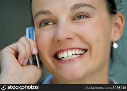 A beautiful dark haired woman talks happily on her mobile phone.