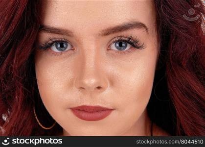 A beautiful face of a young woman in a closeup image with blue eye&rsquo;sand red hair.