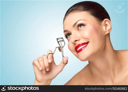 A beautiful fashion girl holding an eyelash curler in her hand as a makeup accessory.