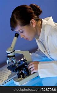 A beautiful female medical or scientific researcher using her microscope.