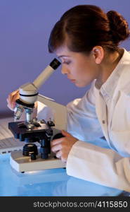 A beautiful female medical or scientific researcher using her microscope.