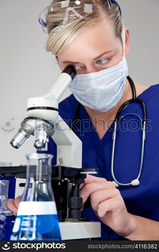 A beautiful female medical or scientific researcher using her microscope for research in a laboratory.