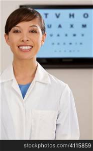 A beautiful female optician shot with an electronic eye test chart out of focus behind her.