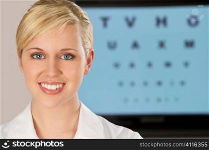 A beautiful female optician shot with an electronic eye test chart out of focus behind her.