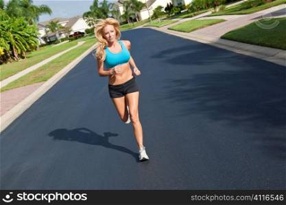 A beautiful fit and healthy blond woman road running down a suburban street in summer sunshine
