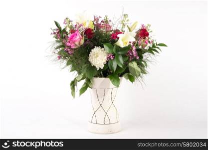 A beautiful flower arrangement in a vase set on a white islolated background.