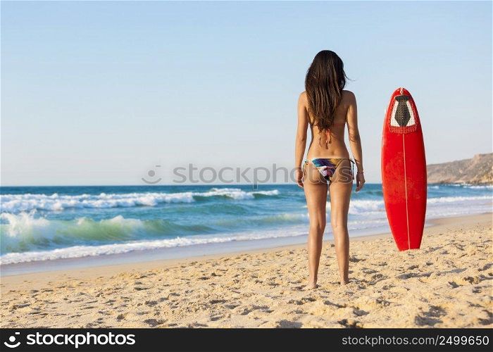 A beautiful girl at the beach posing with her surfboard