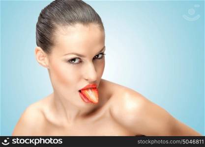A beautiful girl holding a juicy strawberry half in her mouth as a tongue.