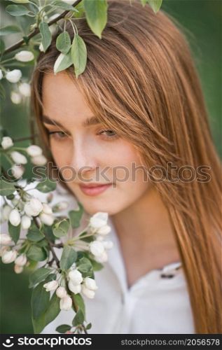 A beautiful girl in a long beige raincoat near a blooming cherry bush.. Portrait of a red-haired beauty in the spring nature 2950.