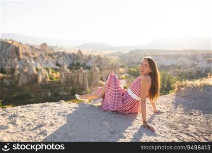 a beautiful girl in a retro dress at sunrise is happy posing against the background of the mountain landscape in Cappadocia