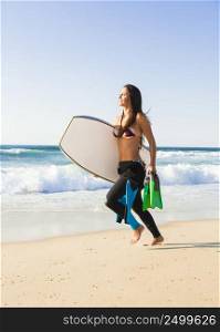 A beautiful girl running at the beach with her bodyboard