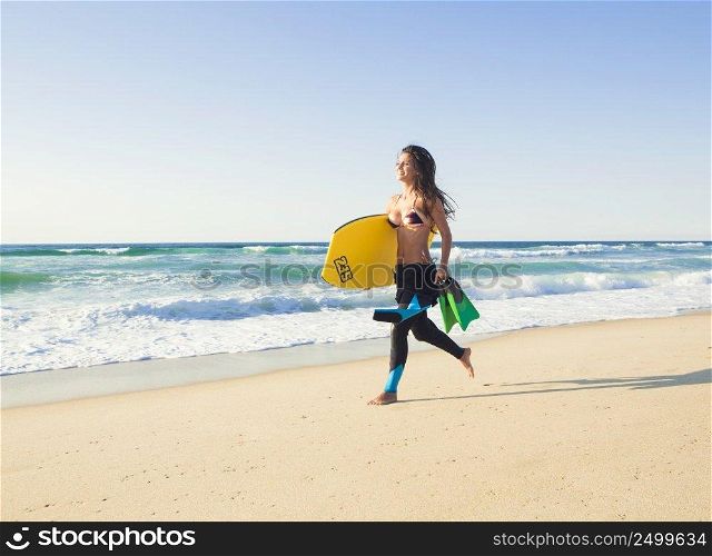 A beautiful girl running at the beach with her bodyboard
