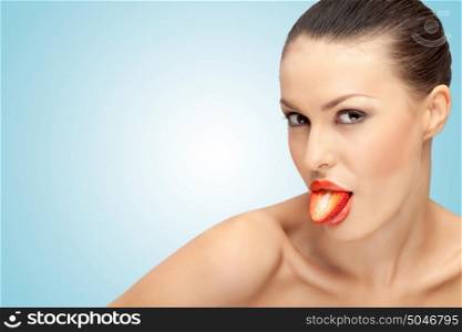 A beautiful girl showing her tongue made of a red strawberry half sexually.