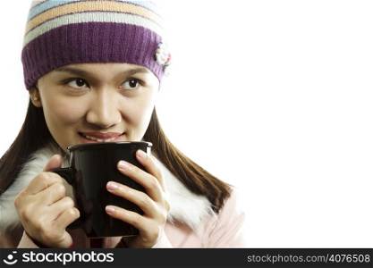 A beautiful girl wearing winter dress holding a cup of hot drink