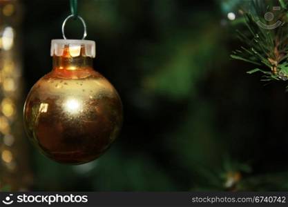 A beautiful golden ornament hanging on the Christmas tree with sparkling bokeh in the background
