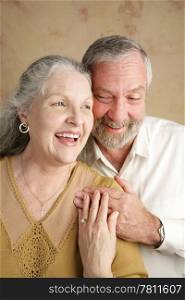 A beautiful gray haired couple in their sixties laughing together. Focus on wife.