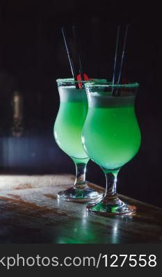 A beautiful green cocktail with white foam and cherry in a tall glass. close-up