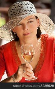 A beautiful green eyed young woman drinking a glass of white wine while bathed in summer sunshine