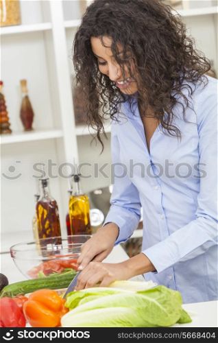 A beautiful happy young woman or girl cutting &amp; preparing fresh vegetable salad food in her kitchen at home
