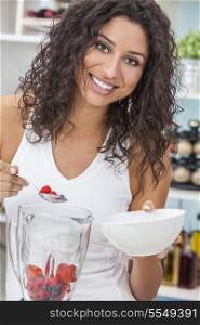 A beautiful happy young woman or girl making a fresh fruit smoothie in her kitchen at home