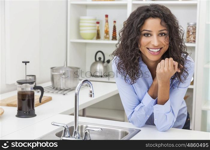 A beautiful happy young woman or girl wearing with perfect teeth and smile relaxing in her kitchen at home