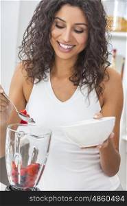 A beautiful happy young woman or girl with perfect teeth preparing fresh fruit smoothie in her kitchen blender at home